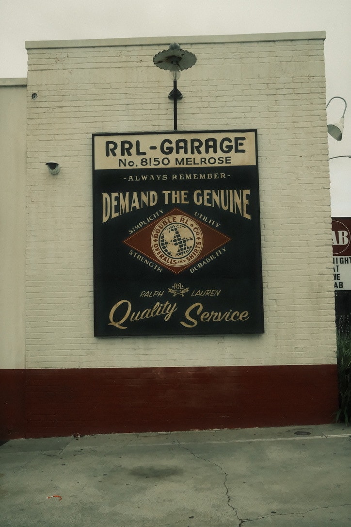 A hand-painted RRL Garage sign on a white brick wall at No. 8150 Melrose: Demand the Genuine, Quality Service.